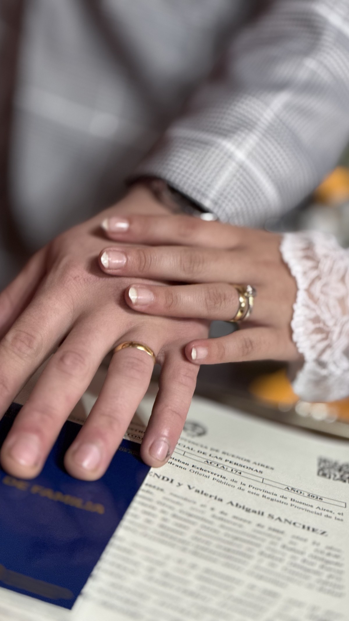 Manos de una pareja con sus alianzas sobre el acta de matrimonio
